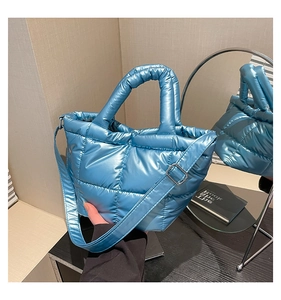 Detail of light blue puffer handbag with metallic finish and adjustable shoulder strap