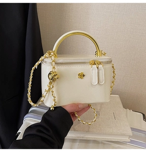 Détail du sac vanité en cuir verni blanc avec camélia doré et poignée métallique
