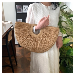 Detail of hand-woven semi-circular straw handbag with intricate natural texture