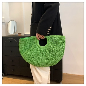 Detailed texture of a bright green woven straw handbag with a crescent moon silhouette