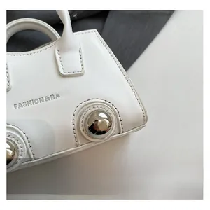 Detail of white leather mini bag featuring silver spherical studs and logo text