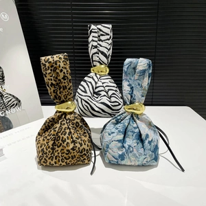 Leopard and zebra print wristlet handbags with gold oval metal clasps on a white display
