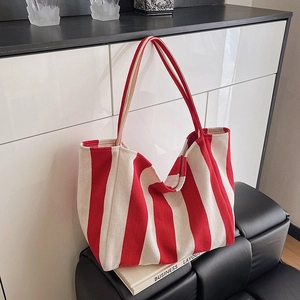 Red and white vertical striped canvas bucket bag displayed on a black bench for daily use