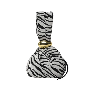 Sac à main moderne motif zèbre avec un grand fermoir goutte en métal doré sur fond blanc
