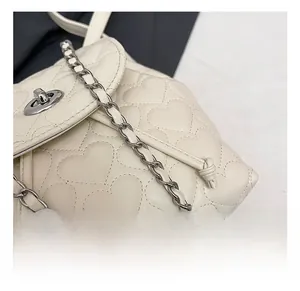 Close-up of heart-quilted leather surface with silver turn-lock and chain strap