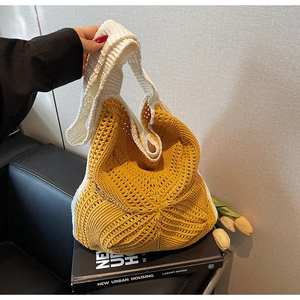 Detail of yellow hollow knit handbag with white handles on a decorative book and flowers