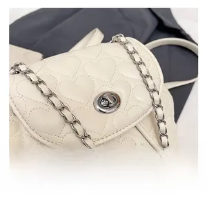 Close-up of metal twist lock and heart quilted leather texture on white backpack