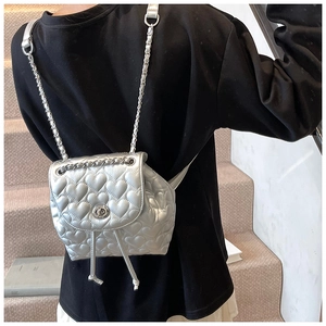 Detail of silver heart quilted backpack featuring metallic finish and chain strap