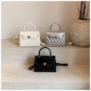 Trois mini sacs à main élégants et matelassés en blanc, argent et noir sur des marches