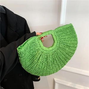 Vibrant green hand-woven straw bag with crescent moon shape and hollow integrated handle