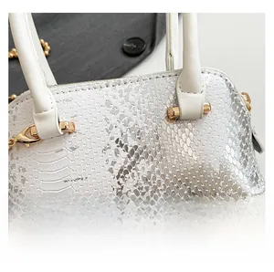 Close-up of silver sequined shell bag featuring metallic snake skin texture and gold hardware