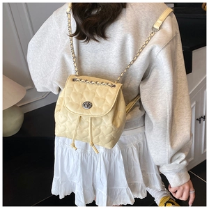 Detail of light yellow quilted mini backpack with heart stitching and chain straps