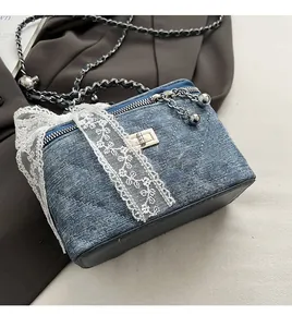 Close-up of blue denim crossbody bag with quilted stitching and white lace bow detail
