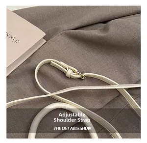 Détail de la bandoulière réglable crème avec boucle en métal doré sur le sac à main