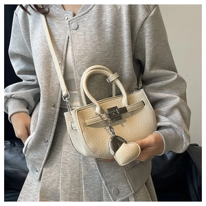 Dettaglio borsa in pelle bianco crema con chiusura in metallo e ciondolo a cuore