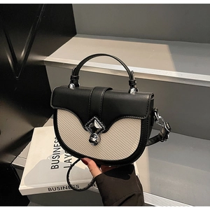 Détail du sac selle contrasté avec boucle argentée sur livre de décoration