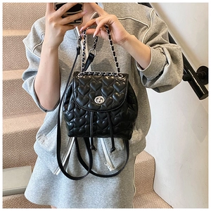 Detail of black heart-quilted backpack with silver twist lock and leather chain handle