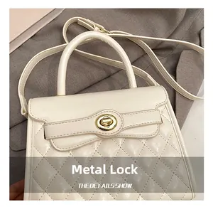 Détail d'un sac à main matelassé blanc crème avec un fermoir rotatif en métal doré