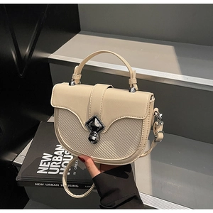 Détail du sac selle avec texture tissée, fermoir rotatif en métal et poignée