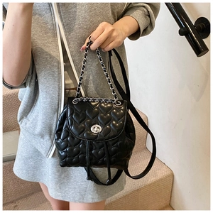 Detail of black heart-quilted backpack with silver chain and twist-lock closure