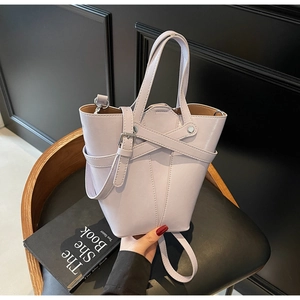 Detail of lilac bucket bag showing front cross strap and polished metal buckle hardware