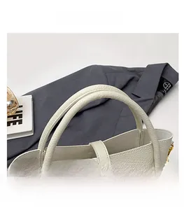 Detail of cream white pebbled leather handbag with sturdy handles and gold-tone hardware