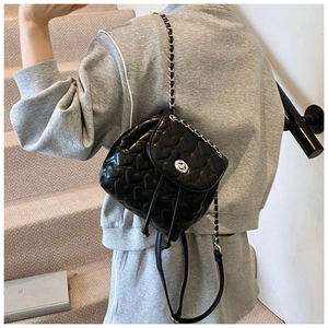 Detail of heart quilted black leather backpack with silver rotating lock on a model