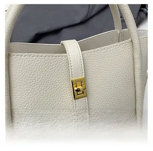 Detail of creamy white pebble leather handbag featuring a sleek golden metal twist lock closure