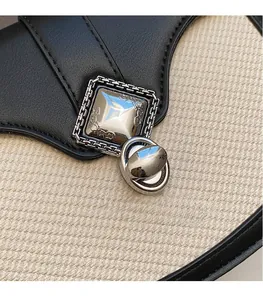 Détail du fermoir argenté et du tissage texturé sur le sac bandoulière bicolore