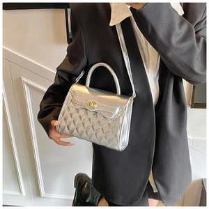Sac bandoulière argenté matelassé avec fermoir doré porté par un mannequin