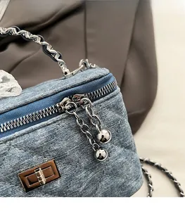 Detail of smooth double zipper and silver metal twist lock on denim box bag