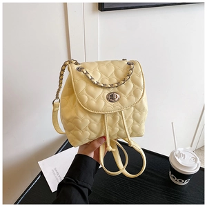 Detail of yellow mini backpack featuring heart-shaped quilting and a metal twist lock