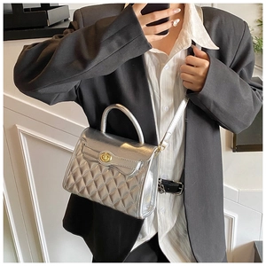 Vue détaillée du sac matelassé argenté avec fermoir doré sur une veste de blazer noire