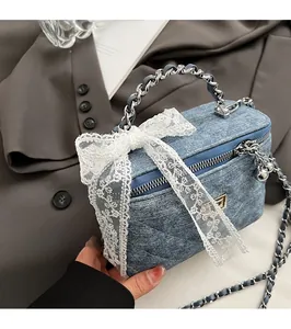 Detailed shot of a blue quilted denim box bag with a large white lace bow decoration
