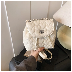Detailed view of heart-quilted white mini backpack with silver metal turn-lock and chain strap