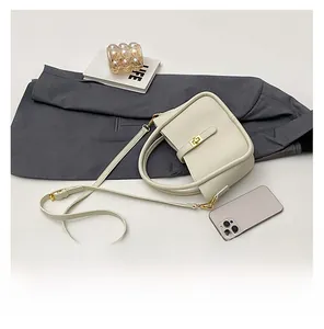 Flat lay of off-white lychee pattern leather handbag with golden lock and thin strap