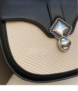 Détail d'un sac besace bicolore montrant le tissu tissé et la boucle en métal argenté