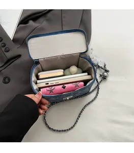 Detail view of denim crossbody bag interior with silver chain and essentials inside