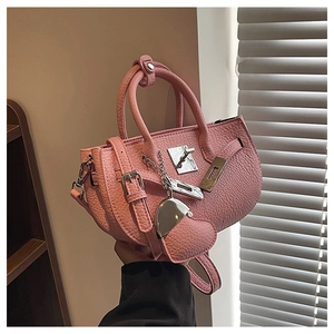 Dettaglio borsa in pelle rosa con chiusura argento e ciondolo a forma di cuore