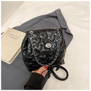 Detail of heart-quilted black leather texture with gold metal twist lock and chain strap