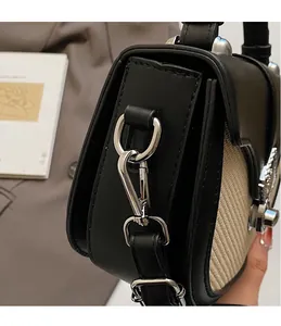 Détail du crochet rotatif argenté sur le sac bandoulière noir et beige