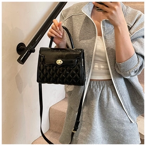 Détail d'un sac bandoulière matelassé noir verni avec fermoir tournant doré et brillant