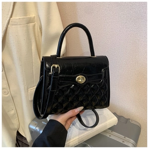 Détail du sac matelassé noir brillant avec fermoir doré et poignée supérieure élégante