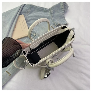 Interno della borsa in pelle color crema con tasca a zip e ciondolo a cuore in argento lucido