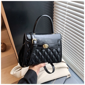 Détail du sac bandoulière en cuir matelassé noir avec fermoir doré et poignée