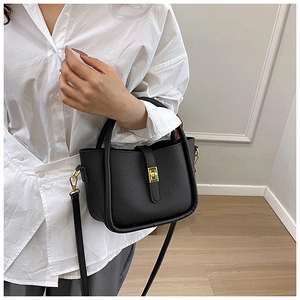 Close-up of black lychee grain leather handbag with gold twist lock and crossbody strap
