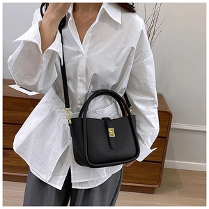 Close-up of black lychee grain leather tote with gold twist lock and rounded handle