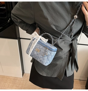 Detail of blue denim quilted box bag with white lace bow and silver chain strap