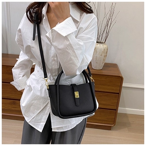 Detail of black lychee grain leather handbag with gold twist lock and shoulder strap
