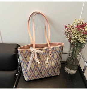 Detail of woven tote bag with colorful geometric patterns and pink leather handles